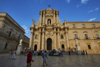 Cathedral of Syracuse, Large cathedral on a square with people and statues under a blue sky,