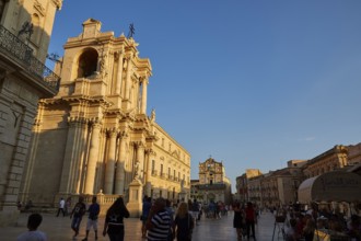Cathedral of Syracuse, people strolling by an impressive cathedral on a square at sunset, Ortigia