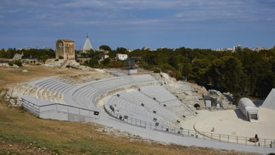 Greek amphitheatre, Ancient amphitheatre surrounded by green trees and historical ruins under a