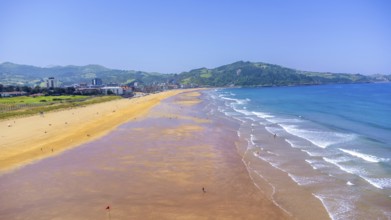 Aerial view of zarautz beach and town on a sunny summer day, showing the golden sand, blue water,