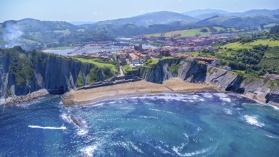 Breathtaking aerial view of zumaia's itzurun beach, cliffs, and cityscape nestled between green