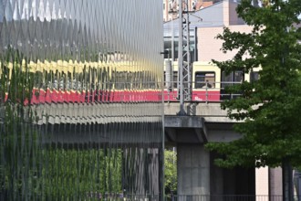 A suburban railway is reflected in the façade of the Futurium in Berlin-Mitte