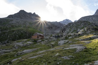 Mountain hut Elberfelderhütte in front of a rocky mountain landscape, sun star in the morning, in