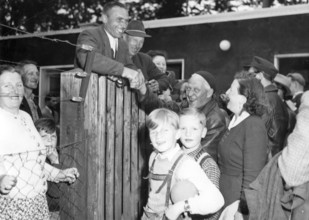 Refugees from the Soviet zone, 1952, A group of people gather around a fence, some smile and shake