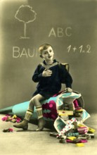 Child giant school cone, 1930s, boy sitting on a fallen school cone in front of a blackboard, toys