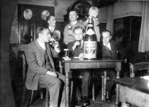 Male company and girls, 1920s, group of men celebrating together with large bottle and glasses in
