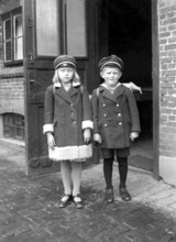 Brother sister pupil, 1920s, Two children in old-fashioned clothes stand seriously in front of an