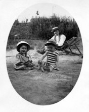 Father with 2 children beach deckchair, 1920s, Two children playing in the sand, an adult in the