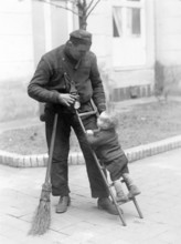 Chimney sweep with child, 1930s, An adult and a toddler share a playful and affectionate moment,
