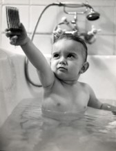 Little boy playing with a wooden car, 1930s, Baby in the bathtub holding up a toy and looking