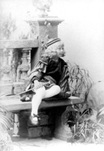 Dressed up girl with sword, 1930s, child in costume sitting on a stone bench, black and white scene