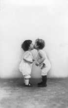 Two little children kissing, 1920s, Two little children giving each other a kiss while looking at
