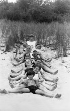 Group on the beach, 1930s, children in black and white swimming costumes smiling on the sand and