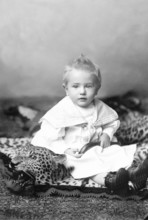 Little boy sitting on a leopard skin, 1910s, A little boy in a traditional outfit sits on a toy