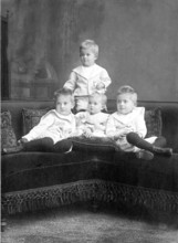 Small children sitting on sofa, 1930s, Four children in classic clothes sitting together on a couch