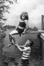 Boy holding girl by the foot, 1920, A boy happily lifting a girl, both in swimwear enjoying the