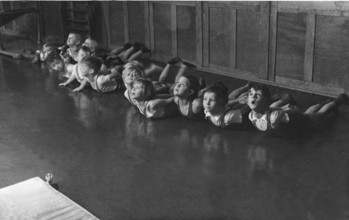 Group of children doing gymnastics, 1930s, children doing floor exercises in a row on the floor,
