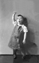 Working class, child raises fist, 1920s, A boy wears an apron and raises his fist energetically,