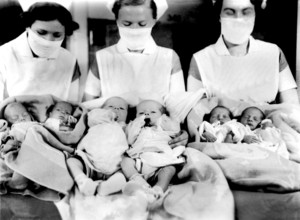 Nurses with newborn babies, 1930s, Several babies are held in blankets by nurses, Historical photo