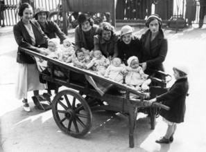 Cartload of babies, 1920s, woman with babies in carts standing on a street, historical photo