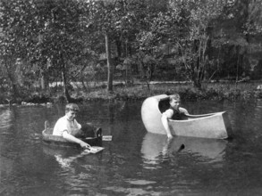 Two boys rowing in funny boats, 1930s, Two men rowing in self-made boats on a body of water,