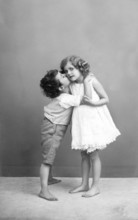 The first kiss, 1930s, Two children in an intimate embrace, Boy gives girl a kiss on the cheek,