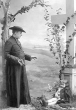 Man blessing a child, 1930s, A priest talks to a child next to a large cross, Historical photo