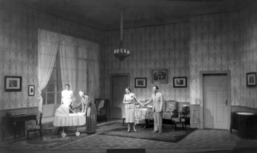 Everyone watching baby in pram, 1930s, A family chatting in a living room next to a pram,