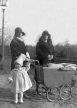 Two woman with pram and child, 1920s, Two woman and a child standing next to a pram, all in winter