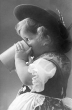 Girl drinking from a beer mug, 1930s, Small child in traditional traditional costume drinking from
