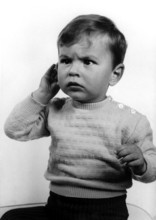 Annoyed child, 1950s, A little boy in a jumper with a questioning expression holds his hand to his