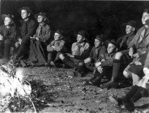 Scout campfire, 1930s, Group of boys in scout suits sitting attentively around a campfire in the