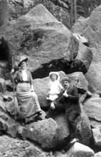 Couple with 1 child hiking, 1910, A family on a rocky outcrop in hiking clothes, holding hats and