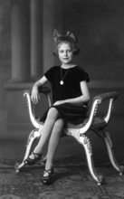 Distinguished girl, 1920, A girl sits solemnly on an ornately decorated chair, wearing a pearl