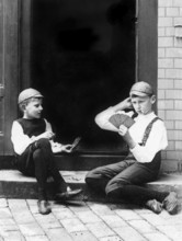 Two children playing cards, 1930s, Two boys in period clothing playing cards on a staircase,