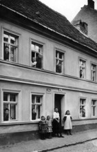 People looking out of windows, 1920, people in a house looking out of windows and standing outside,