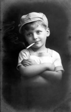 Boy smoking, 1920, Black and white photo of a boy with cap and cigarette in a casual pose,