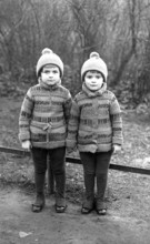 2 boys, twins, 1920, Two identical children in winter clothes standing next to each other outdoors,