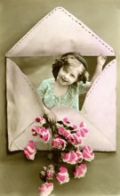Child in an envelope, 1910, Girl looking through a heart-shaped envelope and holding flowers,