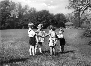 4 children playing, 1930, Four children holding hands in a meadow, Historical photo