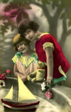 Two girls at play, 1930s, Two children in colourful clothes standing in front of a sailing boat