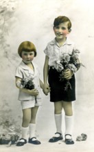 Brother and sister, 1920, Two children in elegant clothes holding flowers, radiating gentleness and