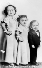 Three children from tall to short, 1920s, children in formal dress posing in front of a studio