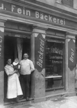 Couple in front of bakery, ca. 1915, Family posing in front of their traditional bakery with