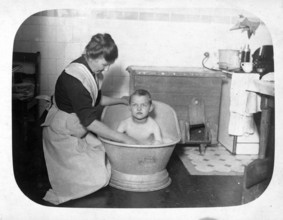 Woman bathing a boy in a small iron bathtub, 1920s, Mother bathing her child in a large tub in a