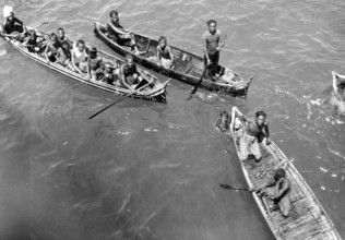 Children in catamarans, Asia, 1930s, People in boats paddling together on a river or lake,