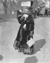 Child in too big fur coat smoking a cigarette, 1920s, Child in thick fur coat with hat and handbag