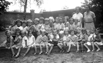 Kindergarten, 1920s, group of children and two woman outdoors, cheerful atmosphere, black and