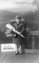 School enrolment, 1920s, A boy with a school bag poses in front of a picturesque landscape,
