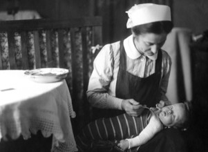 Nanny feeding child, 20s, 1920s, A woman lovingly feeds a baby in a domestic, historical setting,